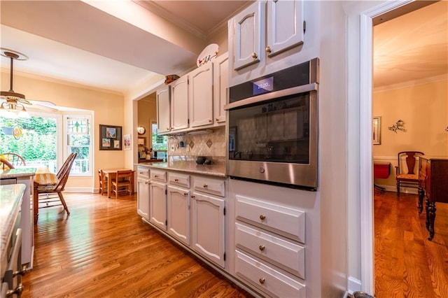 3833 Savannah Sq E, Atlanta, GA 30340 - kitchen with stainless steel oven, crown molding, ceiling fan, wood finished floors, and decorative backsplash