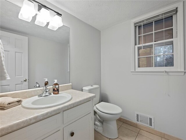 bathroom featuring tile patterned flooring, vanity, toilet, and a textured ceiling