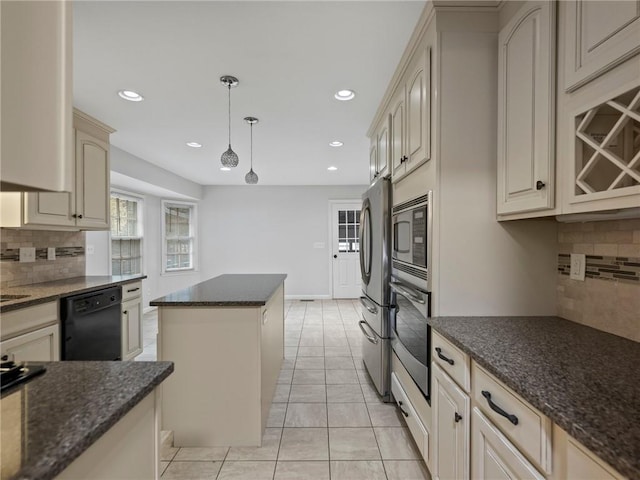 kitchen with a center island, cream cabinets, hanging light fixtures, appliances with stainless steel finishes, and tasteful backsplash