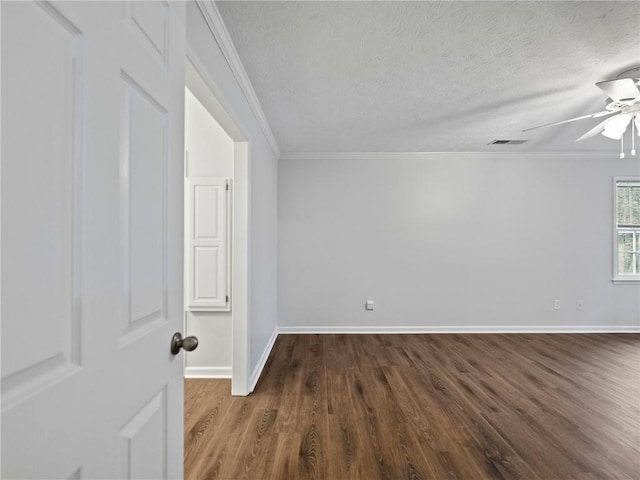 empty room with a textured ceiling, dark hardwood / wood-style flooring, and crown molding