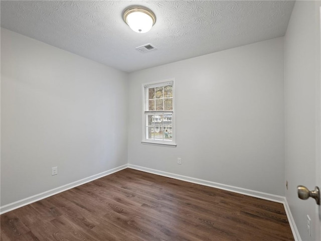 empty room with a textured ceiling and dark wood-type flooring