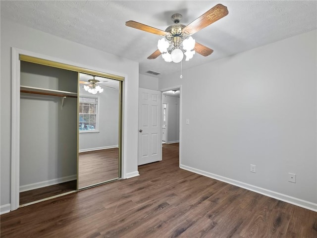 unfurnished bedroom featuring ceiling fan, dark hardwood / wood-style flooring, a textured ceiling, and a closet