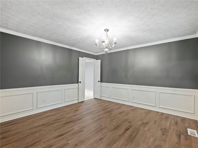 spare room with hardwood / wood-style floors, a textured ceiling, crown molding, and an inviting chandelier