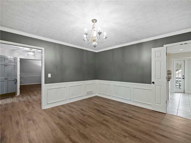 spare room featuring dark hardwood / wood-style flooring, an inviting chandelier, and ornamental molding