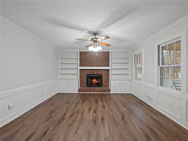 unfurnished living room featuring a fireplace, a textured ceiling, dark hardwood / wood-style flooring, and built in features