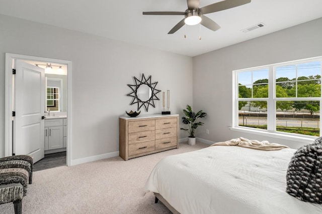 bedroom featuring ensuite bath, ceiling fan, light colored carpet, and sink