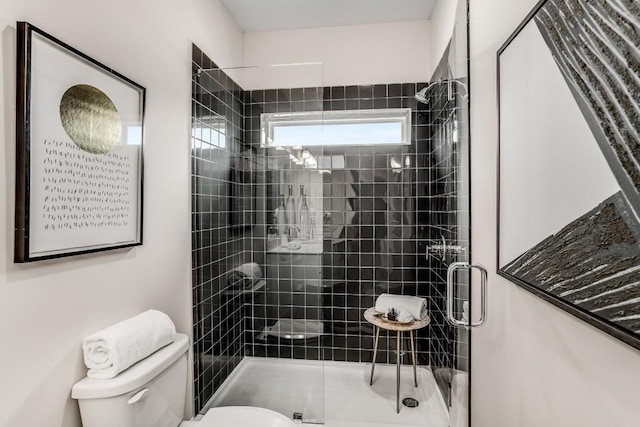 bathroom featuring a shower with shower door and toilet