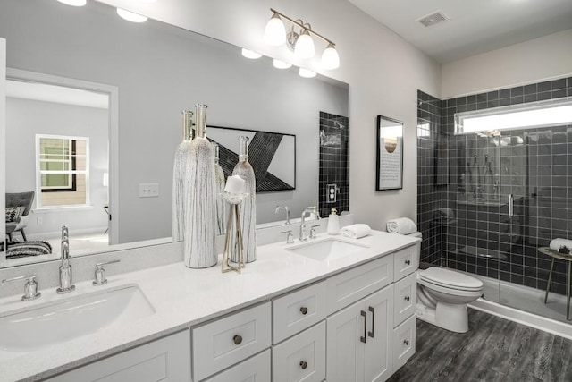 bathroom featuring vanity, tiled shower, toilet, and hardwood / wood-style flooring