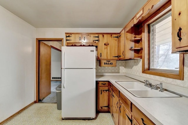 kitchen with a sink, light floors, light countertops, and freestanding refrigerator