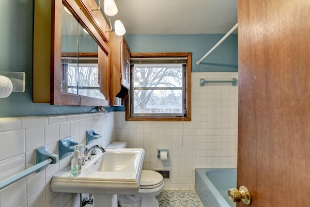 bathroom featuring tile patterned flooring, visible vents, toilet, tile walls, and a sink