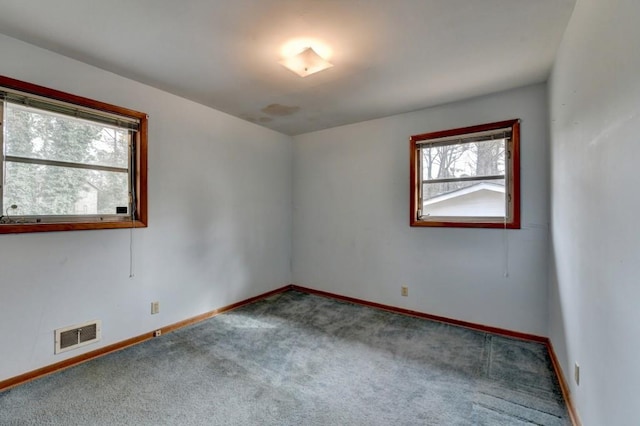 carpeted spare room featuring baseboards and visible vents