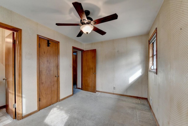 unfurnished bedroom featuring baseboards, light colored carpet, wallpapered walls, and ceiling fan