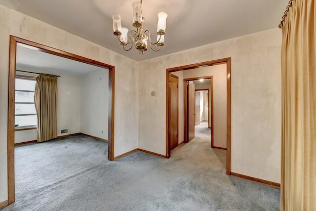 empty room featuring baseboards, a chandelier, and light carpet