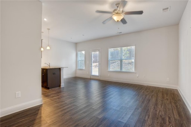 unfurnished living room with dark hardwood / wood-style flooring, ceiling fan, and sink