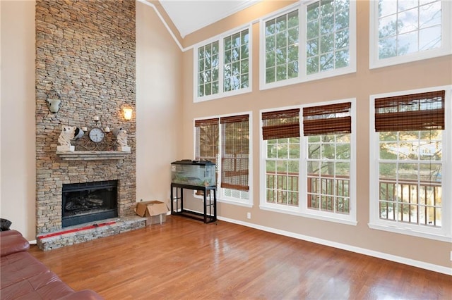 unfurnished living room with a stone fireplace, hardwood / wood-style floors, and a high ceiling