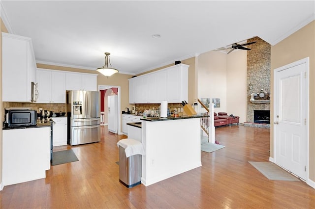 kitchen featuring white cabinetry, light hardwood / wood-style flooring, ornamental molding, stainless steel fridge, and a fireplace