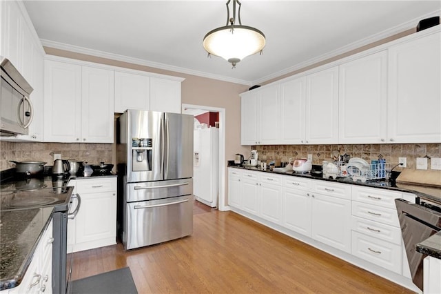 kitchen featuring white cabinetry, stainless steel appliances, decorative light fixtures, and dark stone counters