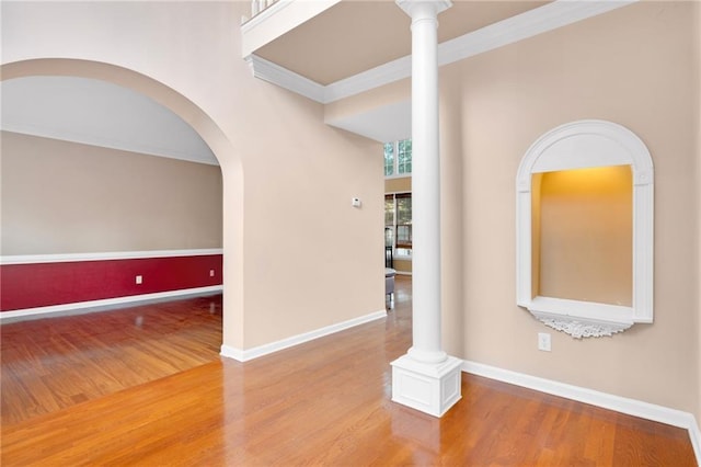 empty room featuring decorative columns, ornamental molding, and hardwood / wood-style floors