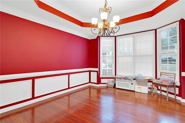 unfurnished room featuring crown molding, a raised ceiling, hardwood / wood-style floors, and a notable chandelier