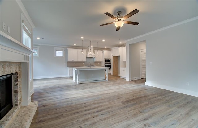 unfurnished living room with crown molding, light hardwood / wood-style flooring, ceiling fan, and sink