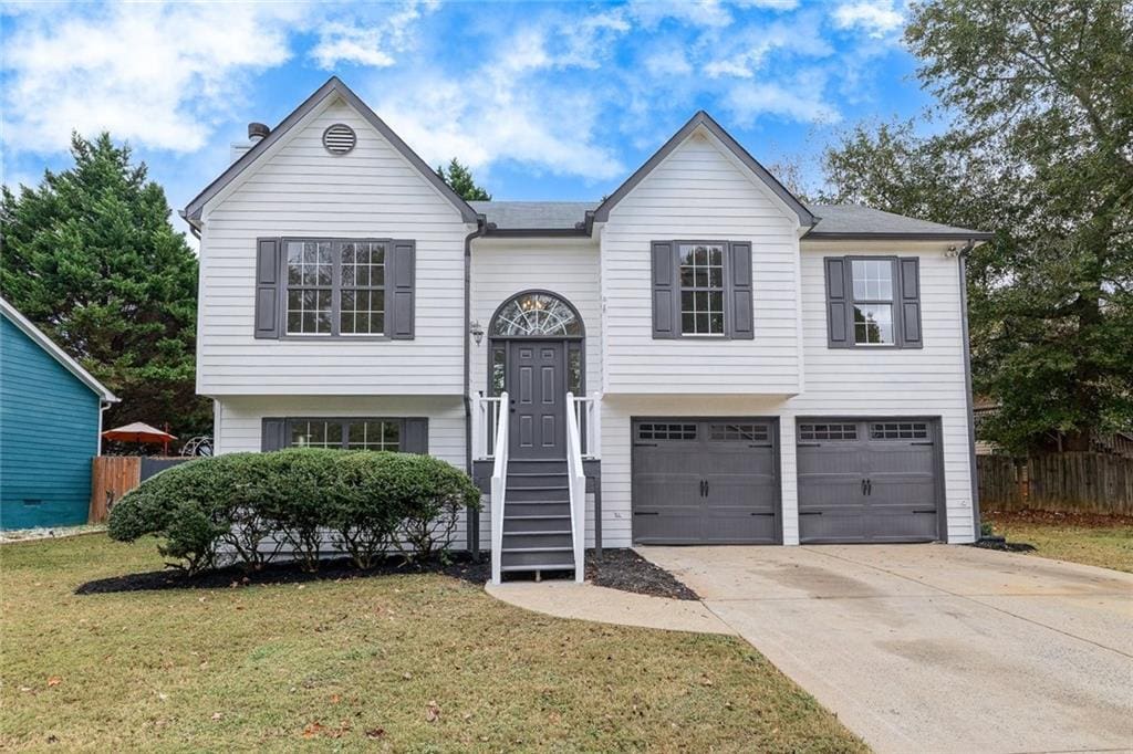 raised ranch featuring a front yard and a garage