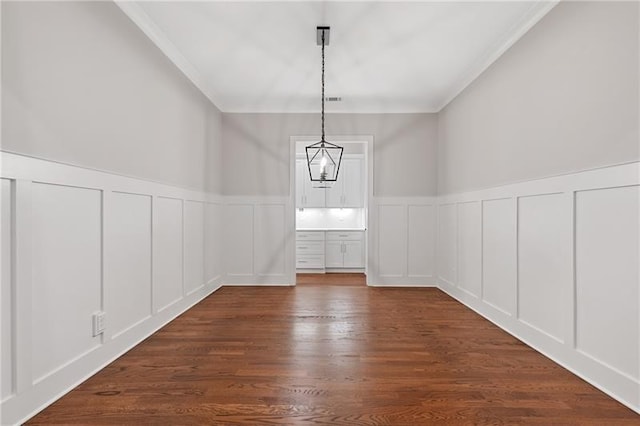 unfurnished dining area featuring ornamental molding and dark hardwood / wood-style floors