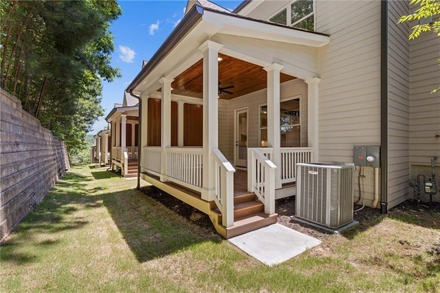 doorway to property with cooling unit, ceiling fan, and a yard