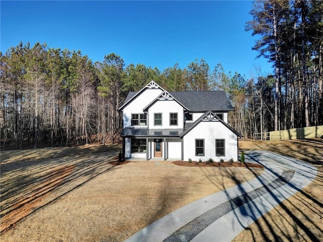 view of front of property featuring metal roof, a shingled roof, driveway, stucco siding, and a standing seam roof