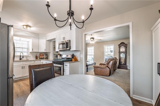 kitchen featuring light stone counters, a sink, stainless steel appliances, white cabinetry, and tasteful backsplash