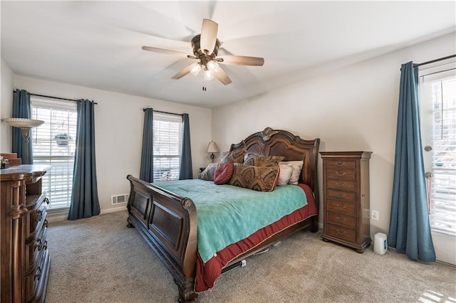 carpeted bedroom with visible vents, multiple windows, and a ceiling fan