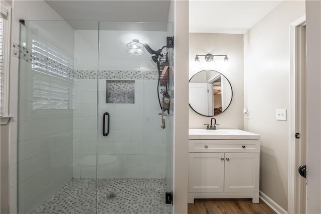 full bath featuring vanity, a shower stall, wood finished floors, and baseboards