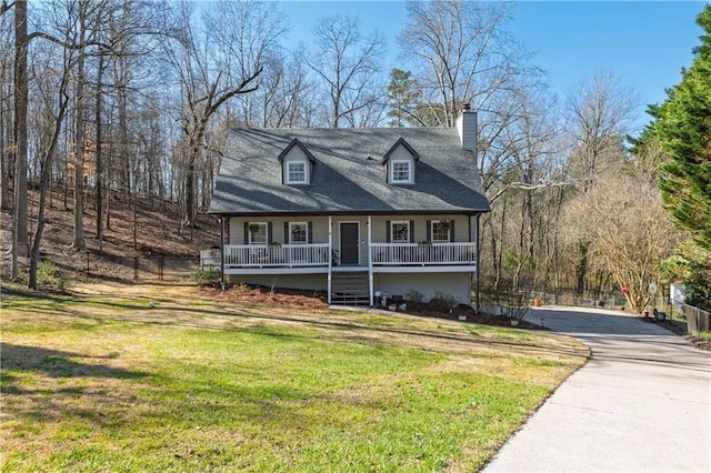 view of front of property featuring a chimney, driveway, covered porch, and a front yard