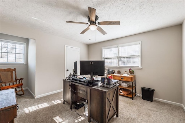 home office featuring light colored carpet, a ceiling fan, and baseboards