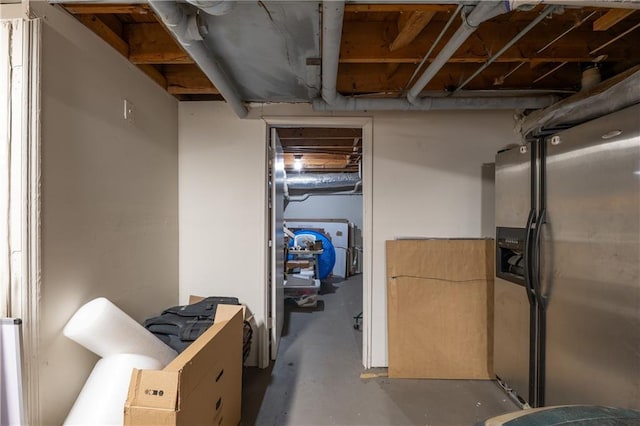 unfinished basement featuring stainless steel refrigerator with ice dispenser