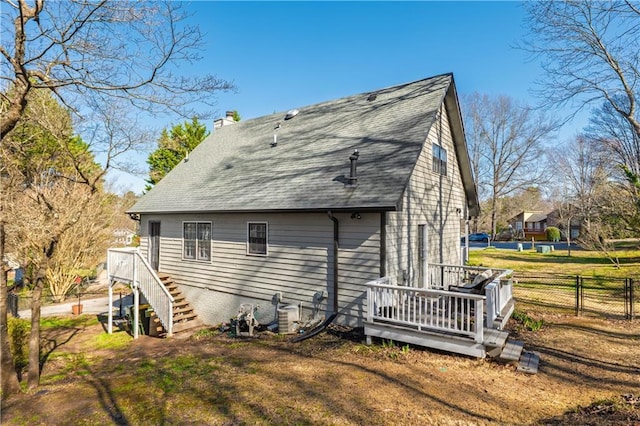 back of house with stairway, fence, a wooden deck, a chimney, and a lawn