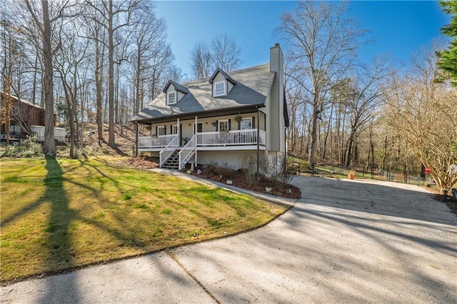 view of front of house with covered porch, driveway, a chimney, and a front yard