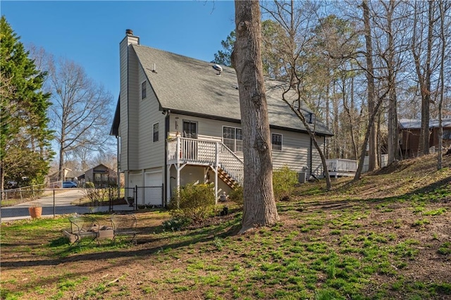 back of house with fence, stairs, central AC unit, a chimney, and an attached garage