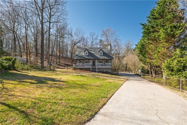 rustic home with aphalt driveway, a chimney, a front yard, and fence