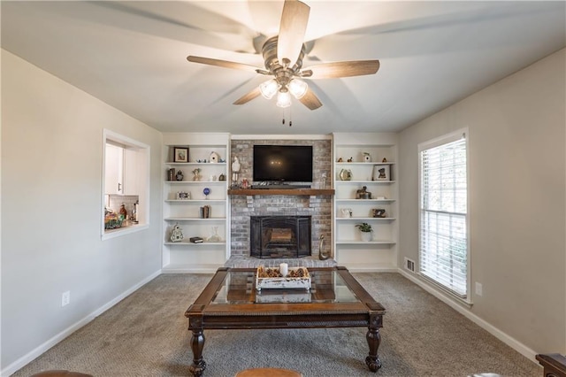 carpeted living room featuring visible vents, baseboards, built in features, a fireplace, and a ceiling fan