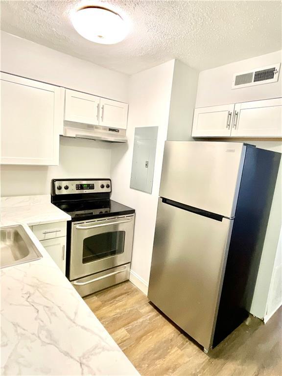 4701 Flat Shoals Rd Unit 68D, Union City, GA 30291 - kitchen with stainless steel appliances, under cabinet range hood, a textured ceiling, white cabinetry, and electric panel