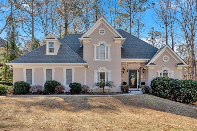 view of front of home with stone siding, a shingled roof, a front yard, and stucco siding