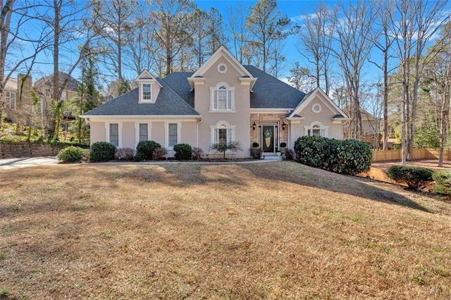 view of front of house with a front lawn, fence, and stucco siding