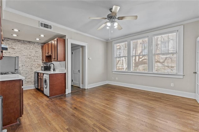 kitchen with a sink, visible vents, washer / clothes dryer, and ornamental molding