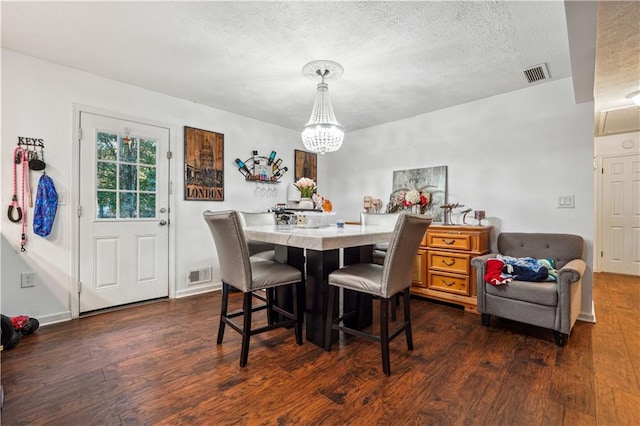 dining area with an inviting chandelier, a textured ceiling, and dark wood-type flooring