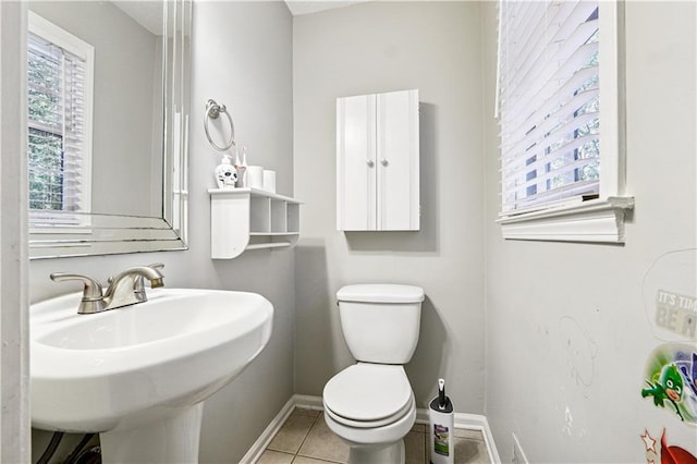 bathroom featuring a healthy amount of sunlight, sink, toilet, and tile patterned flooring