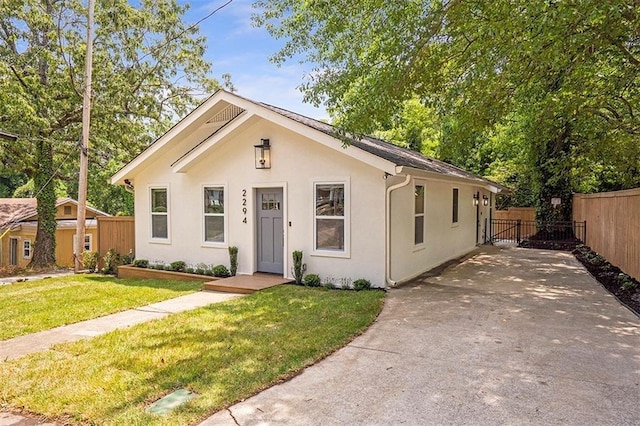 bungalow-style home featuring fence, a front lawn, and stucco siding