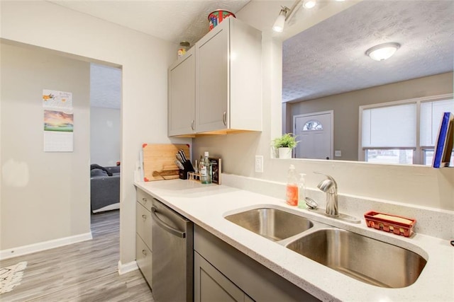 kitchen featuring dishwasher, a textured ceiling, baseboards, and a sink