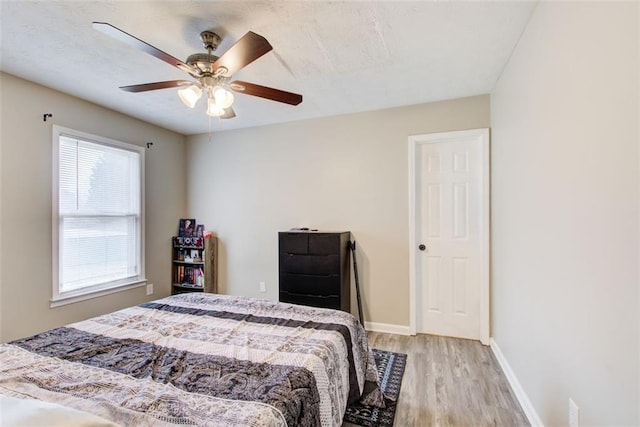 bedroom featuring ceiling fan, baseboards, and wood finished floors