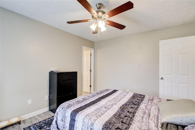 bedroom featuring baseboards, light wood-style flooring, and a ceiling fan