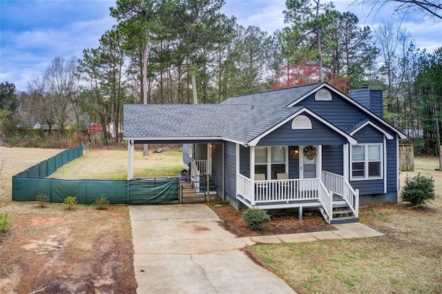 view of front facade with driveway, covered porch, a shingled roof, an attached carport, and a chimney
